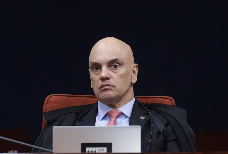 Alexandre de Moraes, de toga, sentado na bancada da Primeira Turma do STF, atrás de um notebook