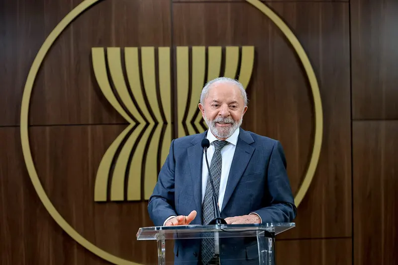 O presidente Luiz Inácio Lula da Silva fala em um púlpito de acrílico, diante de um painel de madeira com o símbolo da Asean