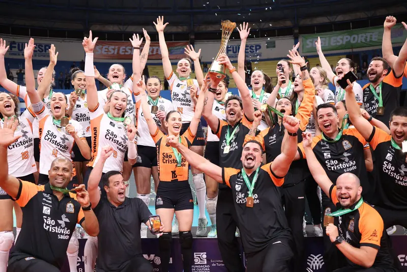 Jogadoras e comissão técnica do Osasco comemoram com o troféu da Supercopa de 2025, de braços erguidos, na quadra